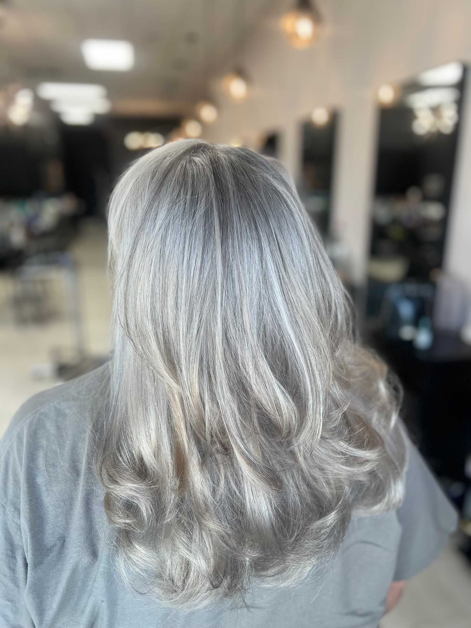 Wavy silver hair in a salon, styled with soft curls.